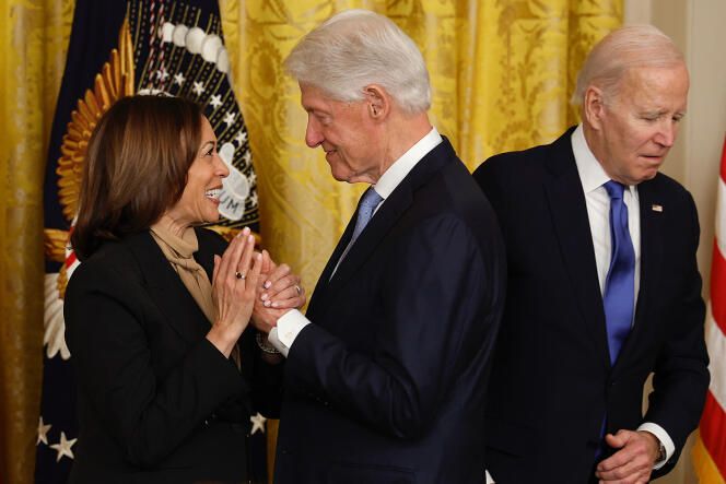 Bill clinton toma la mano de Kamala Harris. Biden aparece al fondo de la foto