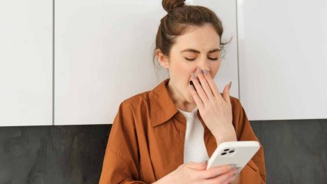 mujer bostezando mientras ve su celular