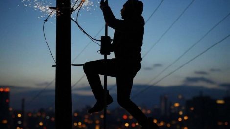La silueta de un hombre, trepado en un poste eléctrico, y se produce un cortocircuito con chispas