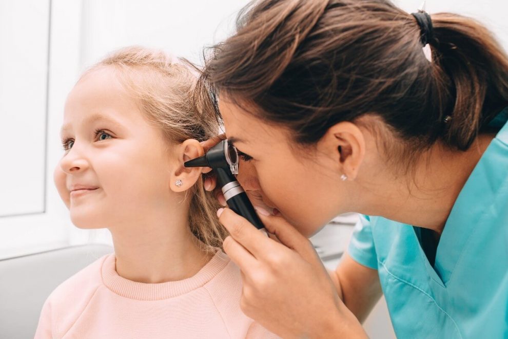 Médico revisando el oído de una niña